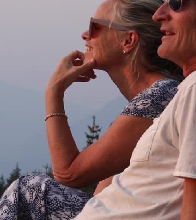 夫妇在俯瞰山脉的壁架上放松