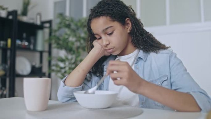 沮丧的非洲裔美国少女吃谷物，食欲不振，情绪波动