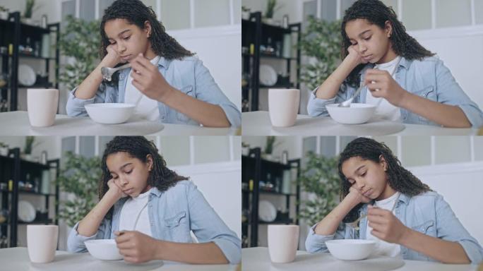 沮丧的非洲裔美国少女吃谷物，食欲不振，情绪波动
