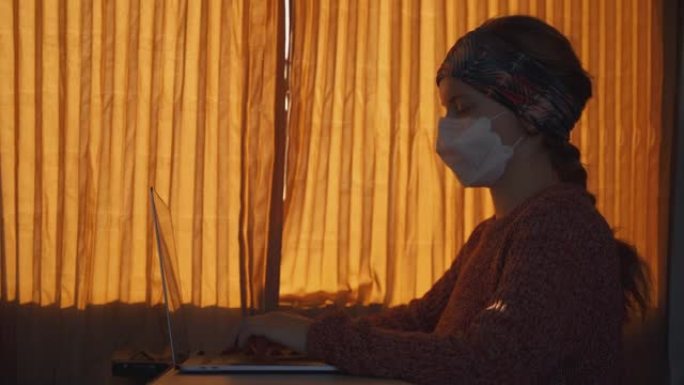 使用笔记本电脑在火车上戴着口罩的年轻女子