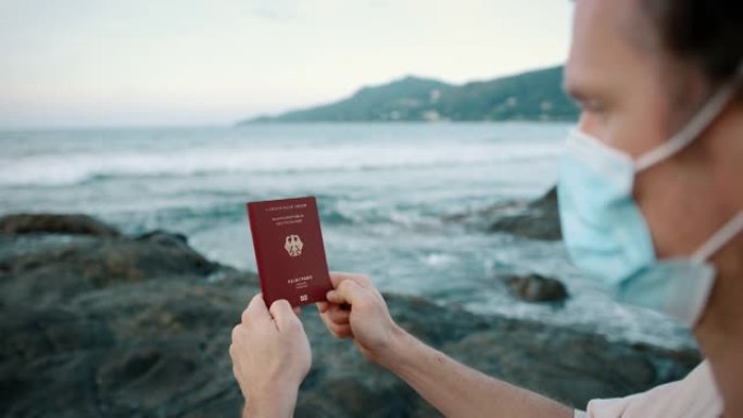 戴口罩的男子在海洋附近持有德国护照