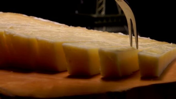 叉子的特写镜头从木板上拿一块法国硬奶酪