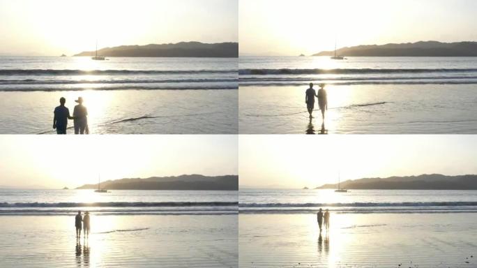 日出时，夫妇在空旷的海滩上散步的鸟瞰图