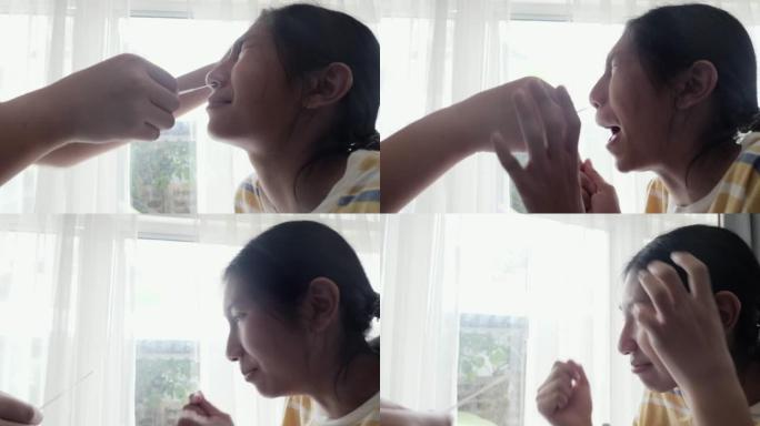 亚洲男孩擦拭他的妹妹鼻子，通过智能手机制作视频，用于在家中使用新型冠状病毒肺炎进行快速测试，然后在网