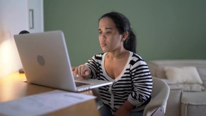在家工作或学习时在笔记本电脑上阅读侏儒症的女人