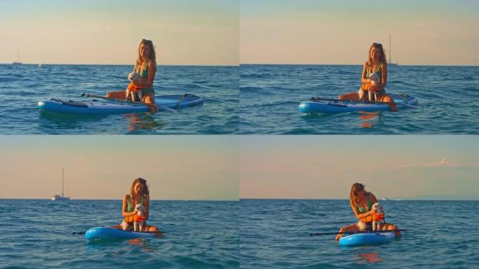 SLO MO肖像，一个女人坐在海上的桨板上抚摸她的小狗