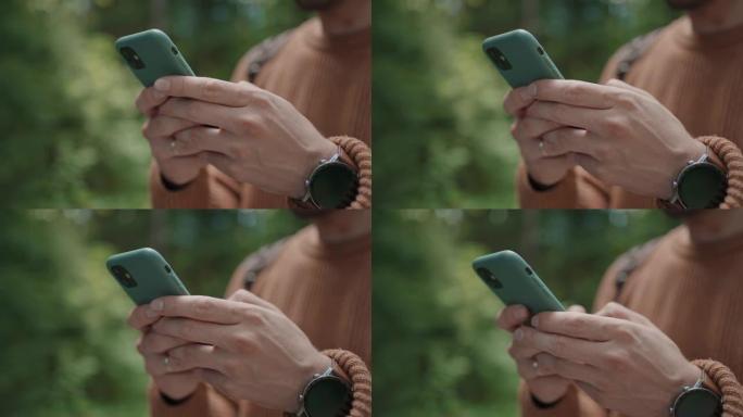 在森林中穿行的男性旅行者手中的手机特写。社交网络导航器和信使。用手机在树林里散步