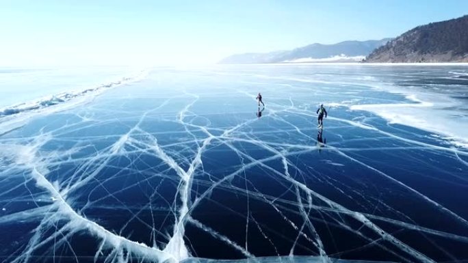 游客漫步在光滑的表面上。风景如画的贝加尔湖裂缝蓝色光泽清澈的冰峰雪堆。最佳北俄罗斯亚洲。冬日晴天蓝天