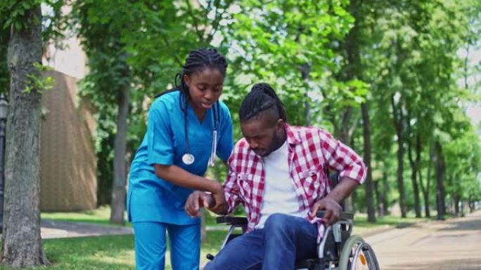护士帮助男性患者从轮椅上站起来，在公园散步，康复