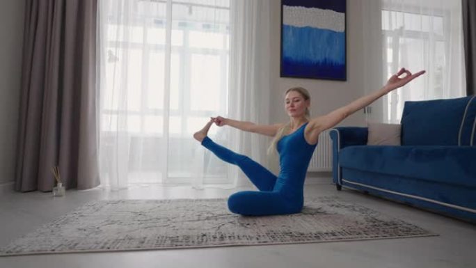 年轻女子在家练习瑜伽，以简单的身体姿势放松，坐在地板上，周围有漂亮的家具。穿着运动服的苗条女人跪在地
