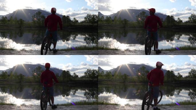 日出时，男子在山湖边缘骑自行车