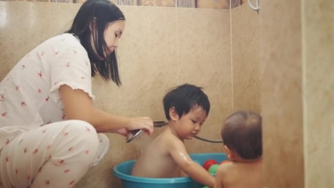 母亲正在家里的浴室给两个儿子洗澡。