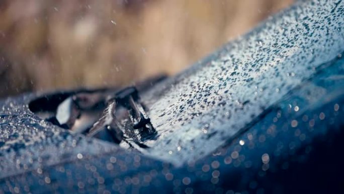 雨滴落在汽车挡风玻璃上，刷子移动以去除水