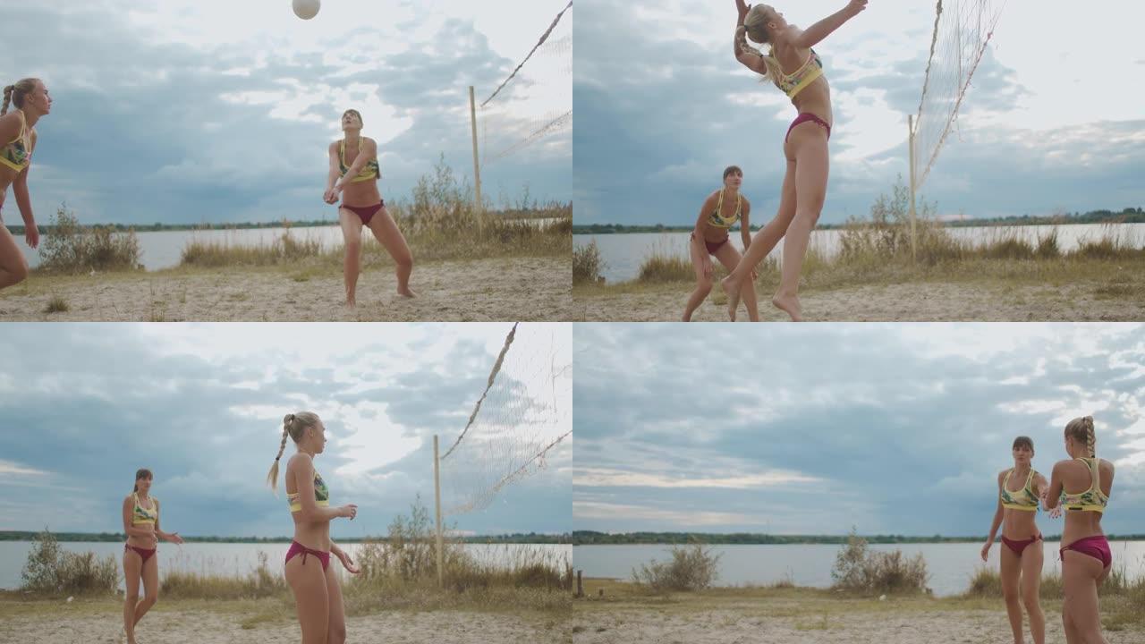 女运动员在沙滩上打沙滩排球在夏天，两个运动员的队伍，女运动员正在跳跃