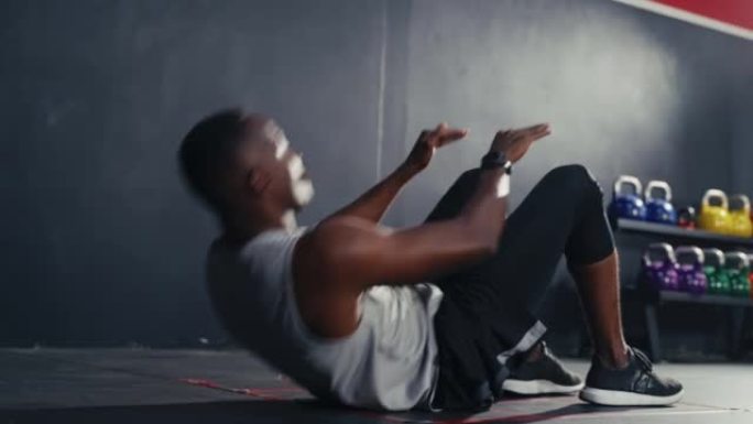 锻炼黑人男子在健身馆内摆动双腿进行健身锻炼和举重。身体锻炼力量和坚实的腹肌肌肉，促进身体健康。