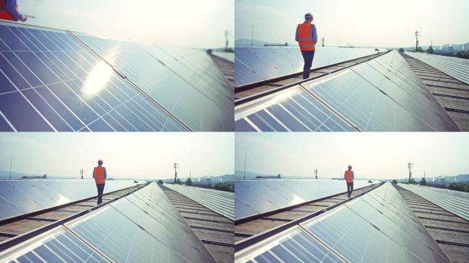 TD男工程师沿着屋顶太阳能发电厂的一排排光伏板行走