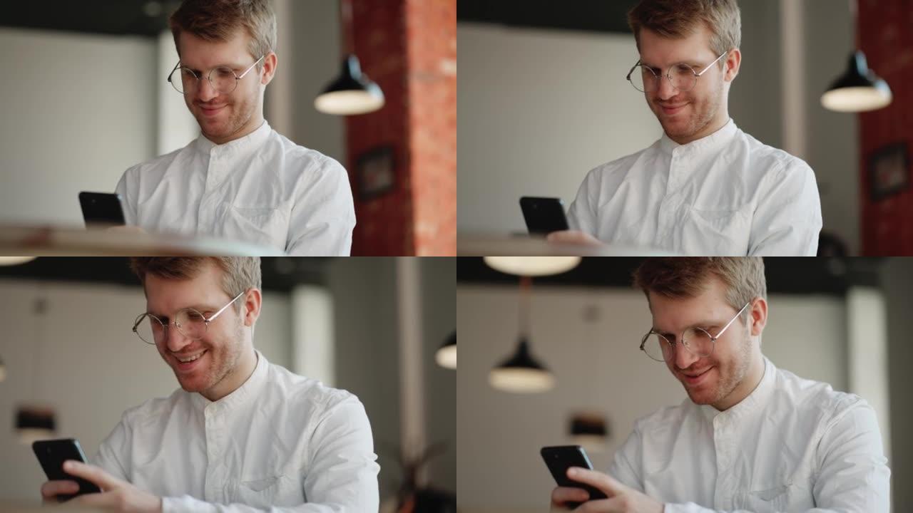 放松的人正在通过现代智能手机上网，微笑着，独自坐在咖啡馆或办公场所