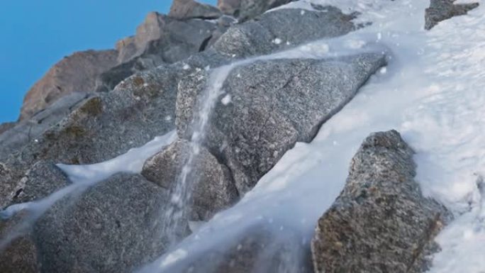 一队登山者在陡峭的山峰上移动。落雪和岩石关闭