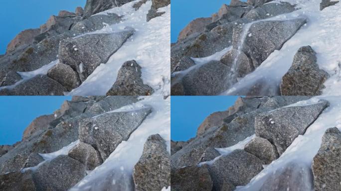 一队登山者在陡峭的山峰上移动。落雪和岩石关闭