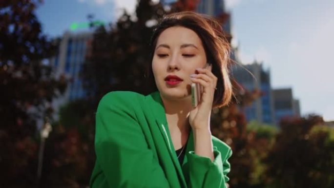 美丽的日本女人在城市公园里用手机聊天的肖像，美丽的亚洲女士