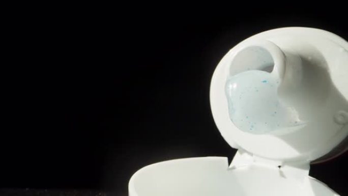 一个开放的管子，里面有白色牙膏和蓝色水晶。多莉滑块极限特写。