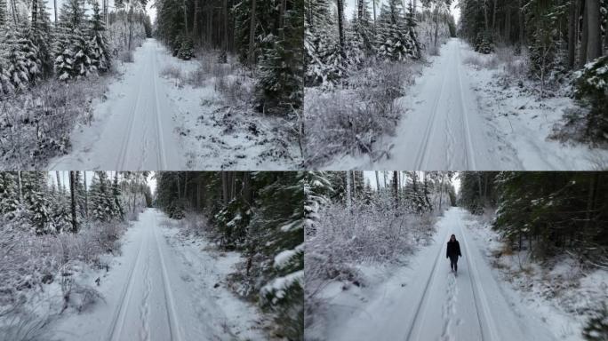 空中无人机拍摄了一名妇女在树林中沿雪道行走的镜头