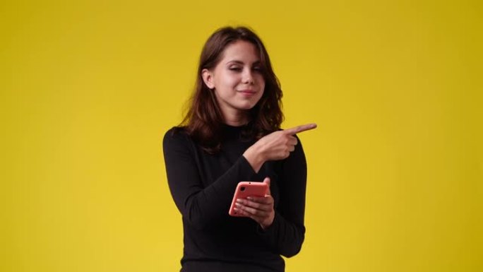一个女孩的4k慢动作视频，手机指向右侧，并在黄色背景上显示拇指。