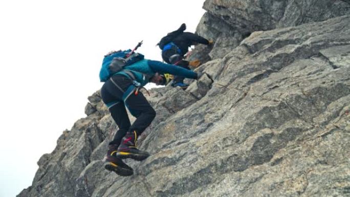 一队登山者在欧洲阿尔卑斯山的陡峭山峰上移动。使用绳索和攀爬设备