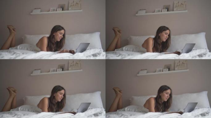 使用笔记本电脑躺在床上的年轻女子