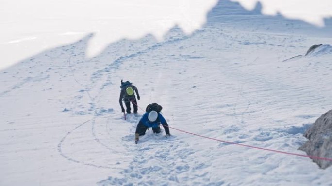 一队登山者在陡峭的山峰上移动。使用绳索和攀爬设备