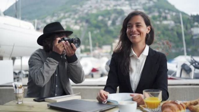 摄影师拍摄了在笔记本电脑上工作并吃早餐的女商人的照片