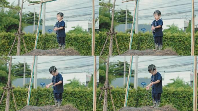 亚洲男孩在户外玩泥浆滑梯后洗泥