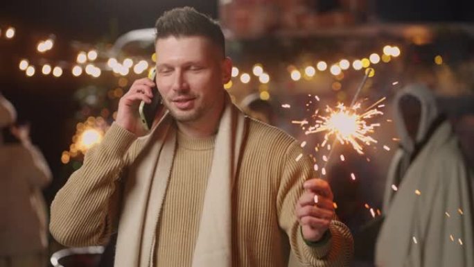 成年男子在圣诞节之夜用手机聊天，摇曳火花并祝贺朋友
