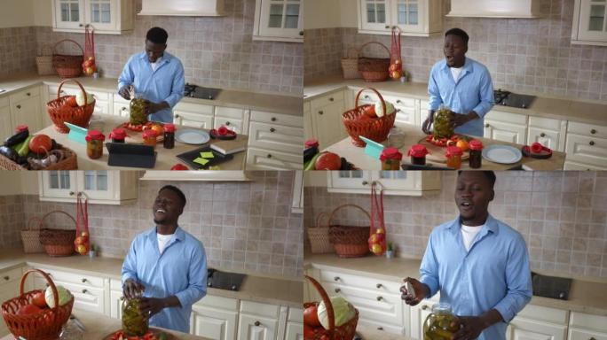 实时摄像机放大到积极的非洲裔美国人在家里的厨房里闻到黄瓜罐头开瓶器的味道。满意的英俊年轻人在室内准备