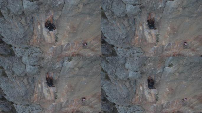 空中无人机拍摄了一名男子攀爬在红色岩壁上的岩石