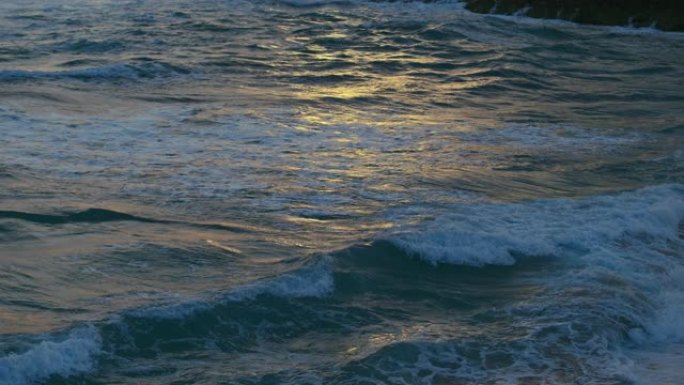 黑暗的大海上的波浪，金色的落日反射在水面上