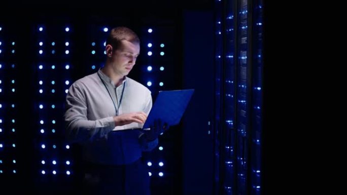 信息数字化的概念: IT专家站在笔记本电脑的服务器机架前，他用触摸手势激活数据中心。网络数据