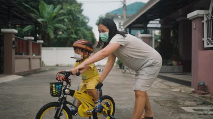 妈妈第一次帮儿子骑自行车。