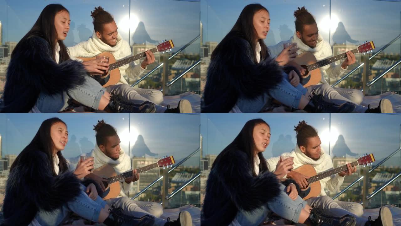 才华横溢的非洲裔美国年轻人弹吉他，亚洲女人在阳光下坐在屋顶上唱歌，阴影掠过。日落时分，快乐无忧无虑的