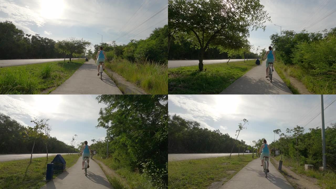 女人沿着丛林小路骑自行车，在马路旁边