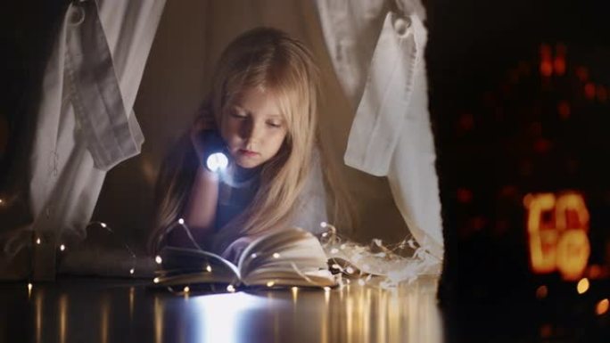 一个小女孩独自用手电筒和花环的光在小屋里读国王。晚上在家看书