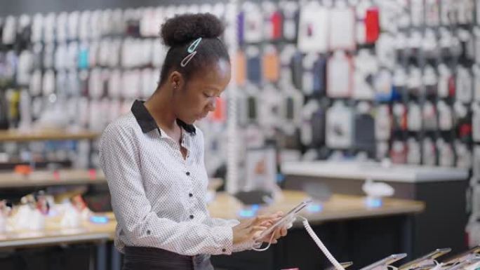 美国黑人女性购物者在电子商店选择手机，黑人女性在零售店购买智能手机