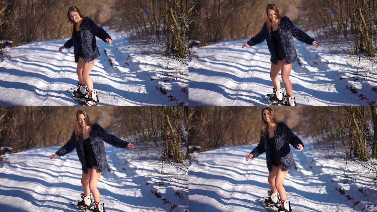 穿着短裤和毛皮大衣的开朗苗条的女人在户外玩得开心。在阳光明媚的冬日户外，用滑雪板拍摄快乐自信美丽的高