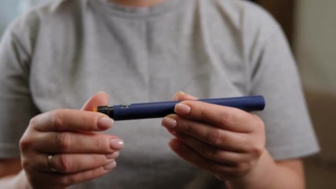 一位糖尿病妇女在注射器笔上拨打正确剂量的胰岛素的特写镜头。