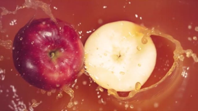 红苹果随着飞溅落在果汁上，分成两半。