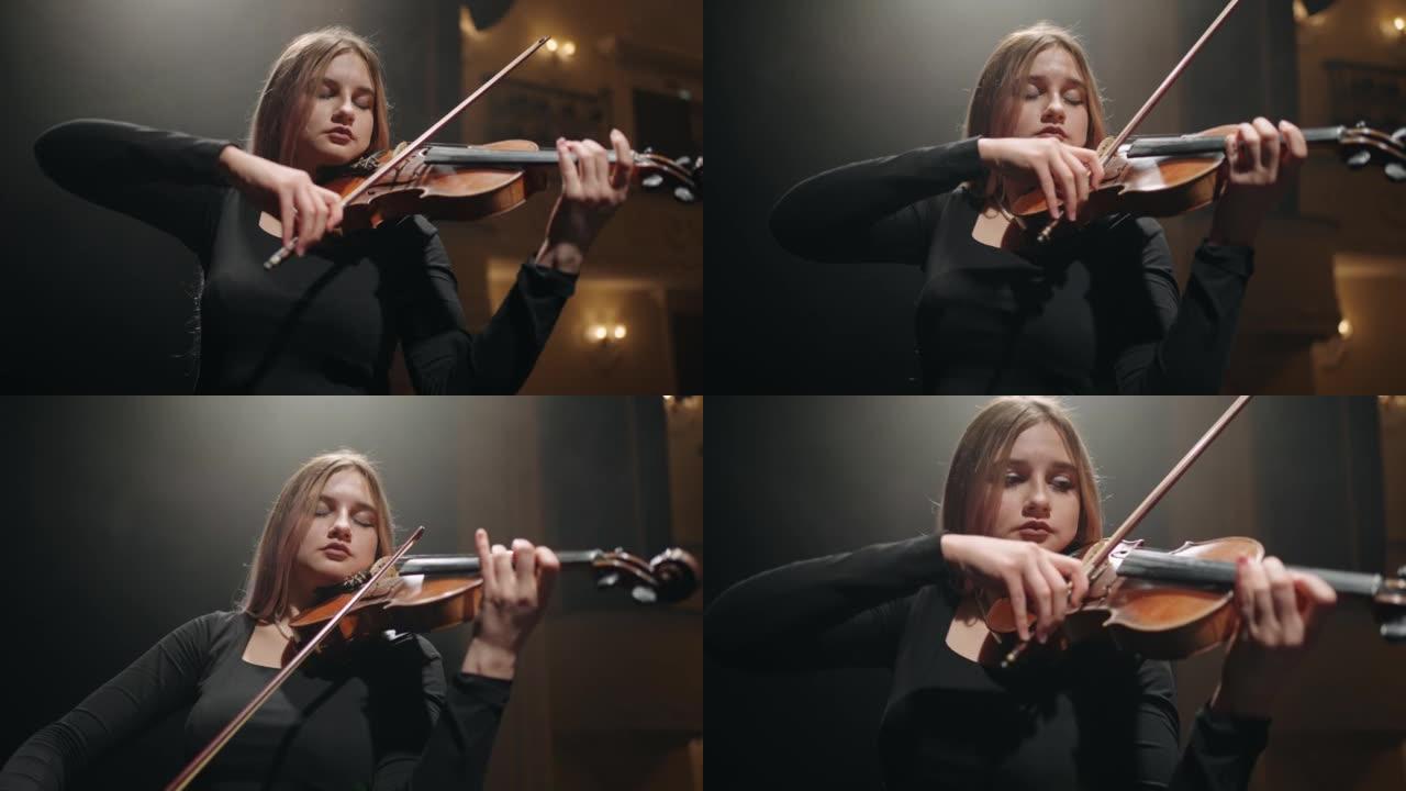 年轻女子小提琴家在音乐厅拉小提琴，小提琴女人肖像，经典音乐音乐会，管弦乐队第一把小提琴，现场独奏家
