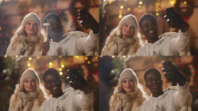 快乐的黑人和他美丽的金发女友在圣诞派对上通过智能手机自拍视频