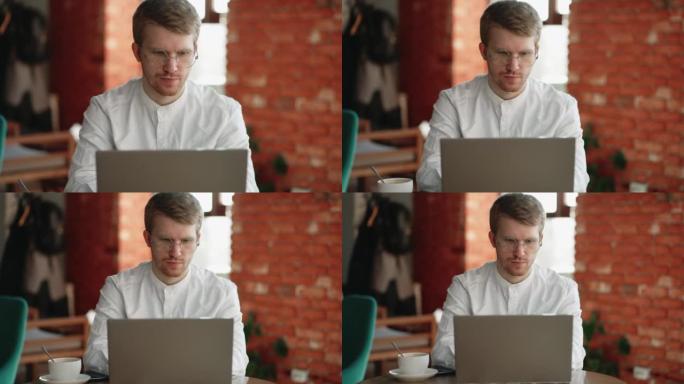 咖啡馆里的严肃男人正在用笔记本电脑在线聊天，在网上聊天中输入消息并发送电子邮件