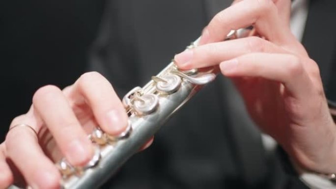 长笛手中的长笛，特写镜头，管弦乐队的音乐家，彩排或音乐会的铜管乐队