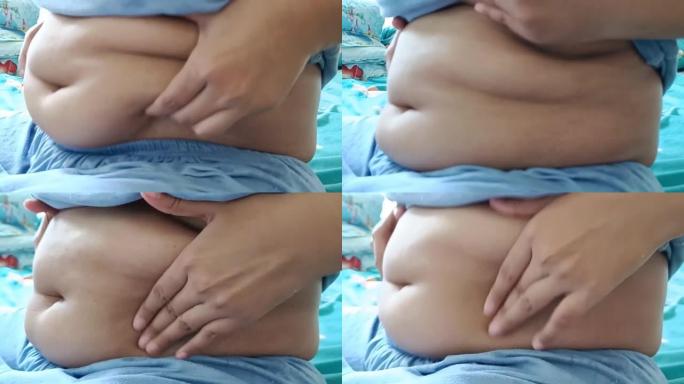 侧视图。寒酸胖胖的亚洲女人坐着露出肚子。你需要注意你的健康和锻炼。